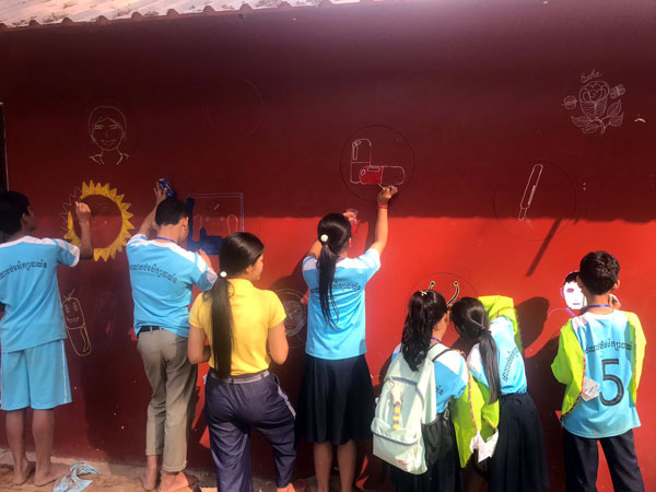 Des élèves peignent une fresque sur un mur
